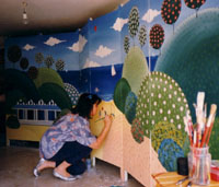 Laura mentre dipinge un paravento per bambini stile Naif